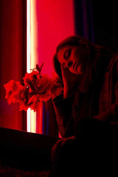 mujer triste bajo luz roja que sufre cancer de pancreas biodescodificacion
