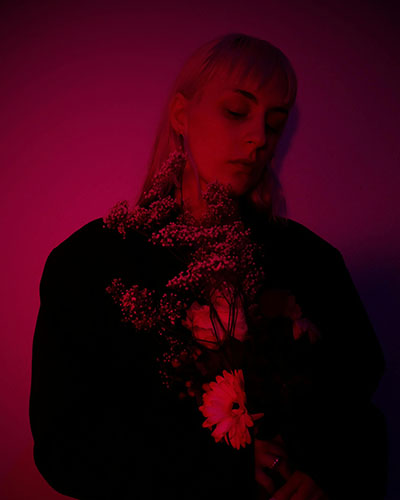 habitacion oscura con mujer que sostiene flores siente dolor emocional tras fibromialgia