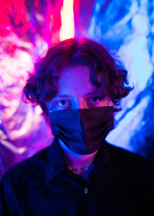 chico con mascarilla fondo rosa y azul neon biodescodificacion de la gripa