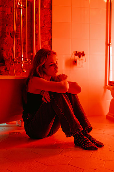 baño con luz roja y mujer dolorida por los sintomas que describe biodescodificacion infeccion urinaria