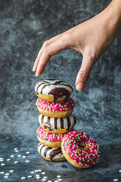 mano agarrando una pila de donuts para llenar el vacio existencial y las negativas emociones y adicciones