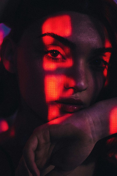 luces rojas sobre rostro de mujer enfadada con colitis cronica en biodescodificacion