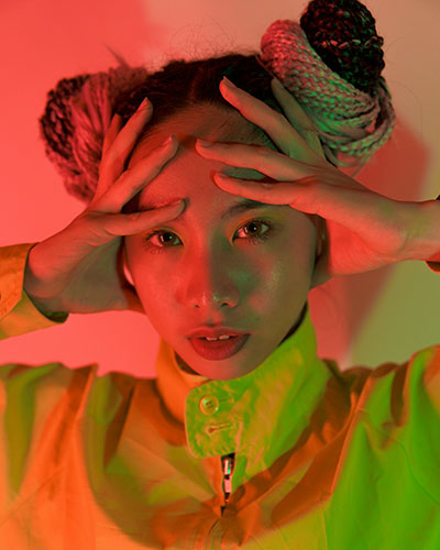 chica iluminada con tonos rojos y verde con emociones que se acumulan