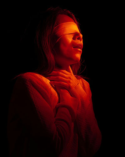 mujer iluminada con ojos tapados representa sintomas segun biodescodificacion angustia