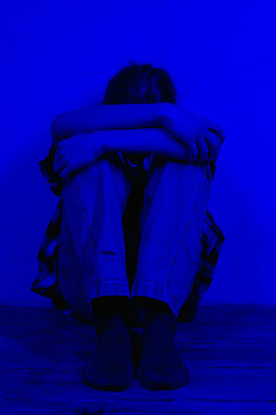 persona agazapada en habitacion con luz de neon azul oscuro biodescodificacion y neumonia miedo oculto