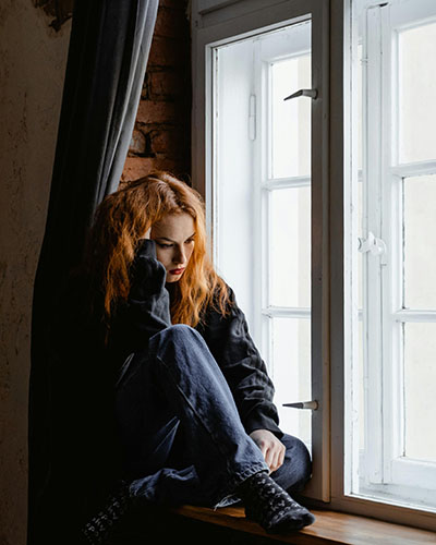 mujer preocupada al lado de una ventana pensamientos en bronquios inflamados segun biodescodificacion